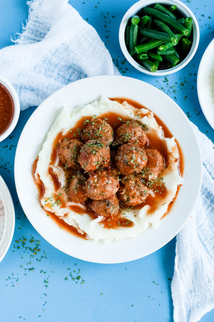 Sweet cider BBQ meatballs recipe served over buttery mashed potatoes — easy fall comfort food with apple cider BBQ glaze.