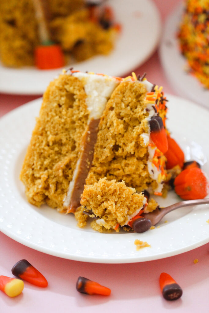 Pumpkin Party Sprinkle Cake covered in orange, yellow, and brown sprinkles and topped with candy corn and candy pumpkins.