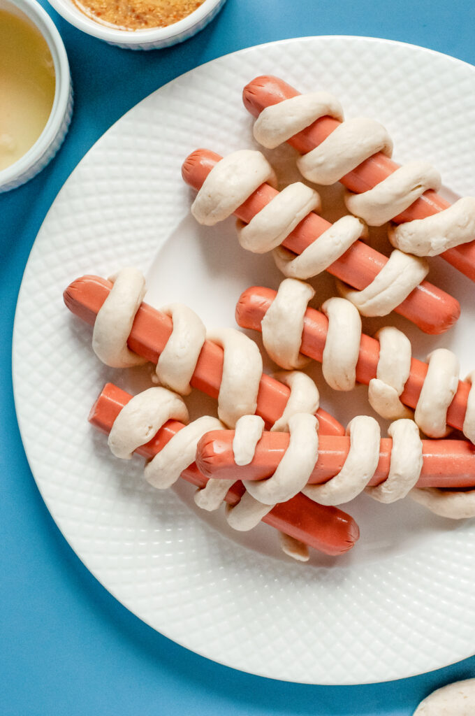 An image of hot dogs wrapped in Pillsbury Grand Biscuits ready to be cooked.