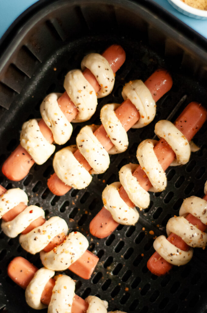 An image of hot dogs wrapped in Pillsbury Grands biscuits in an air fryer.